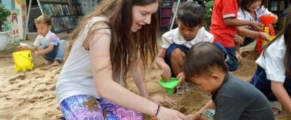 As part of her Projects Abroad service learning project in Cambodia for middle school students, a volunteer plays with a young child at a kindergarten. Part of the Experiential Learning model in Cambodia for middle school students, is for students to help at a kindergarten.